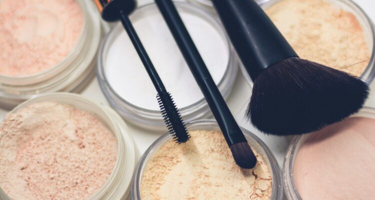 three makeup brushes on top of compact powders