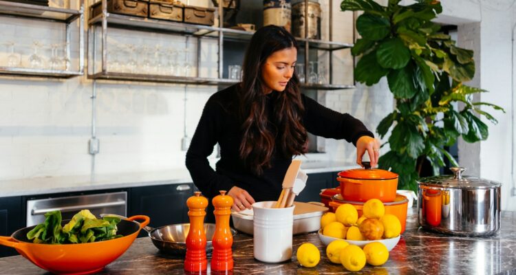 woman standing in front of fruits holding pot's lid