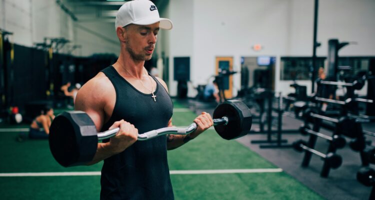 man in black tank top and white cap holding black and gray dumbbell